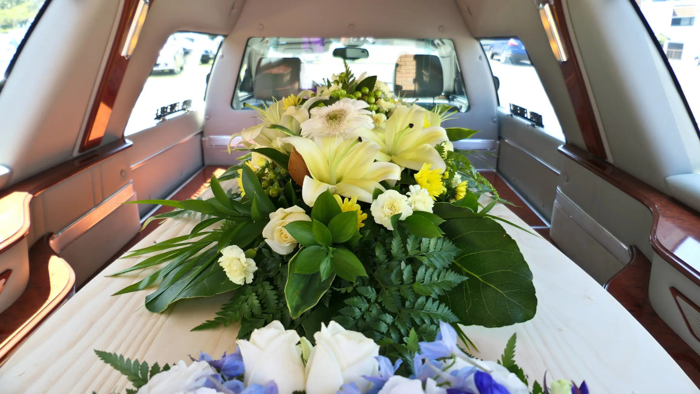 Funeral flowers inside a hearse with casket.
