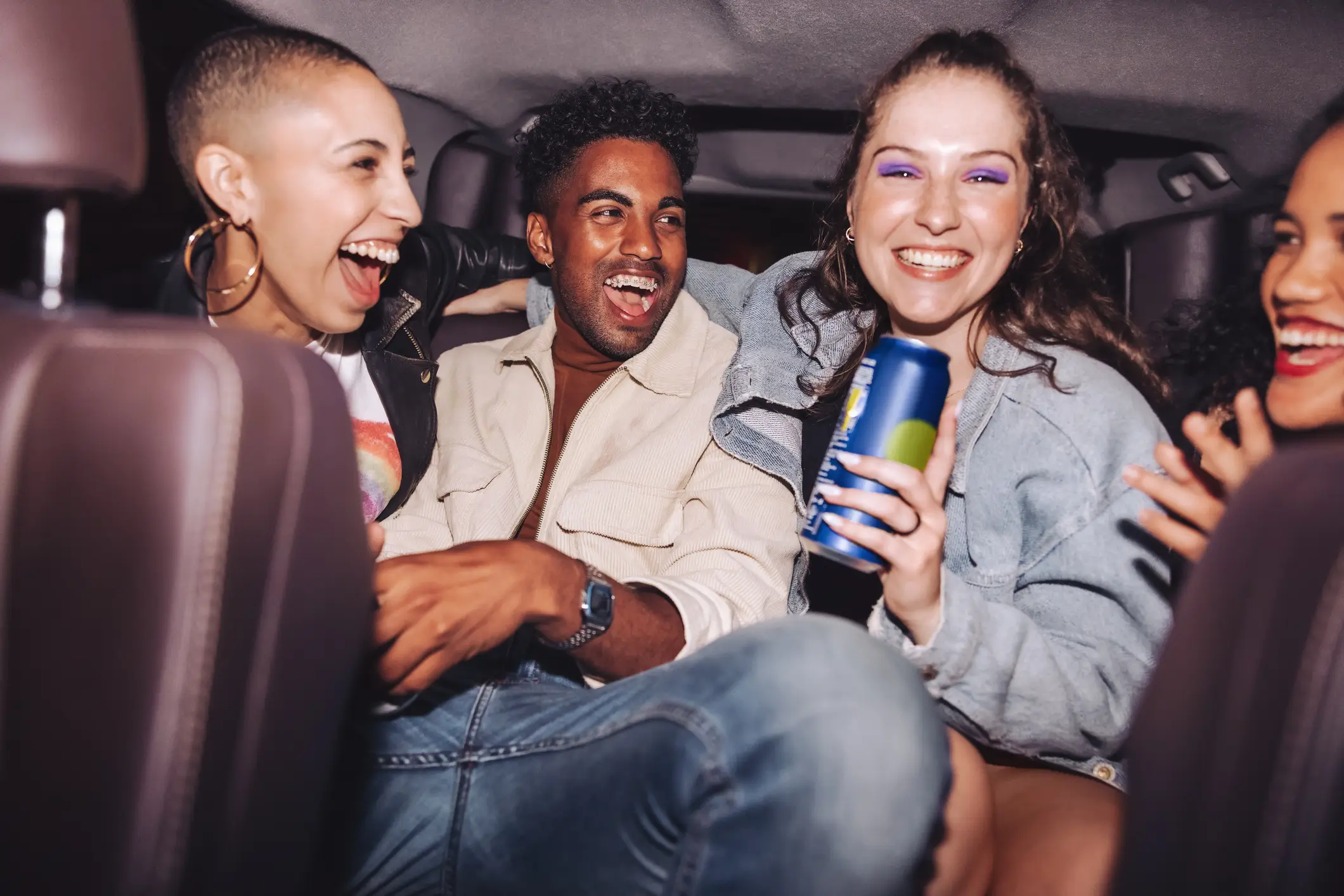 Friends laughing and enjoying drinks in car.