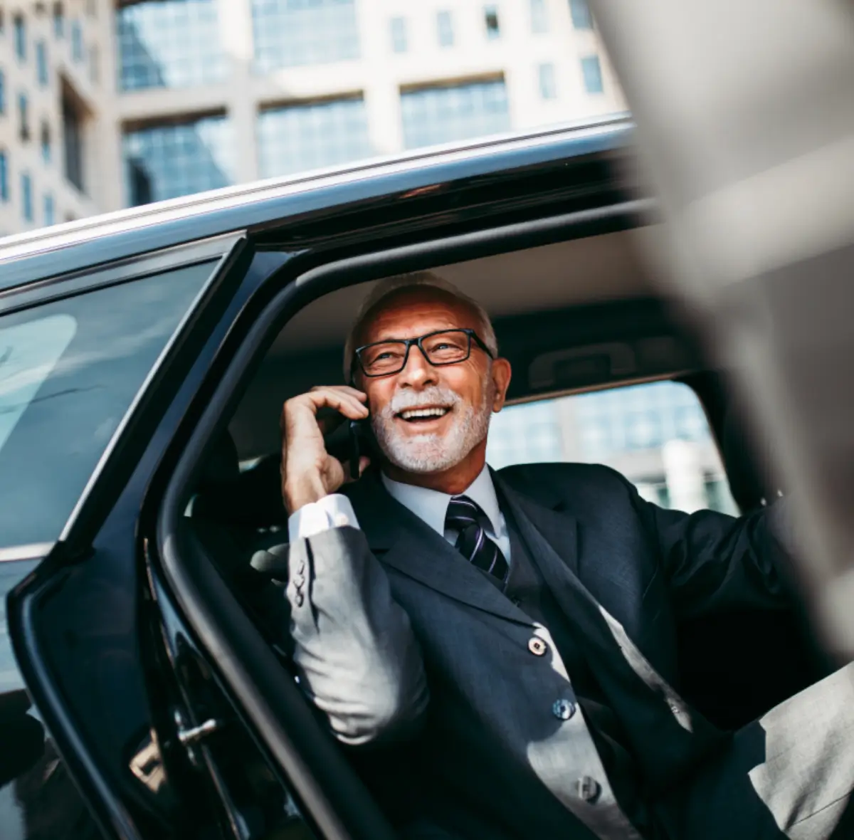 Man in suit smiling, talking on phone.