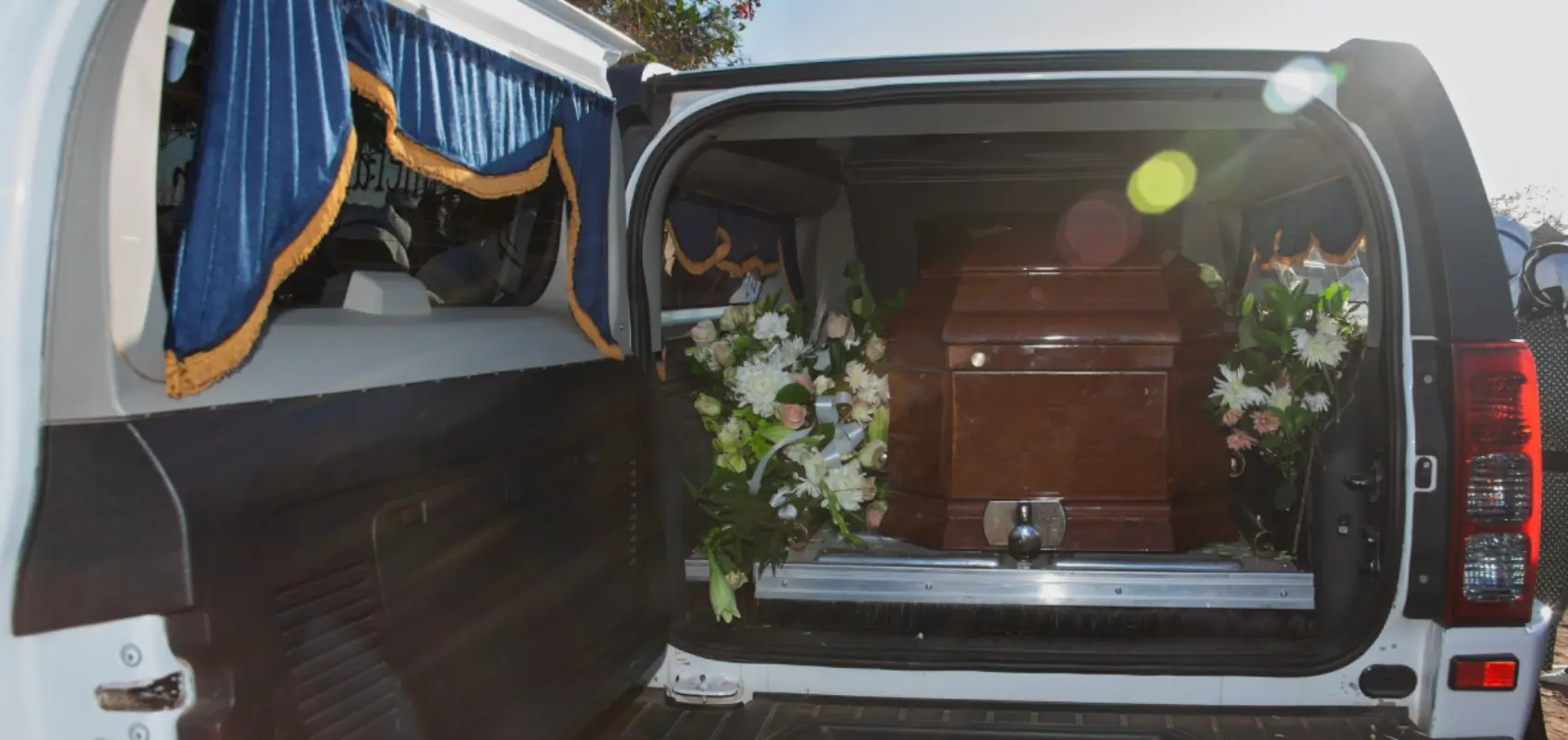 Casket inside a hearse with floral arrangements.