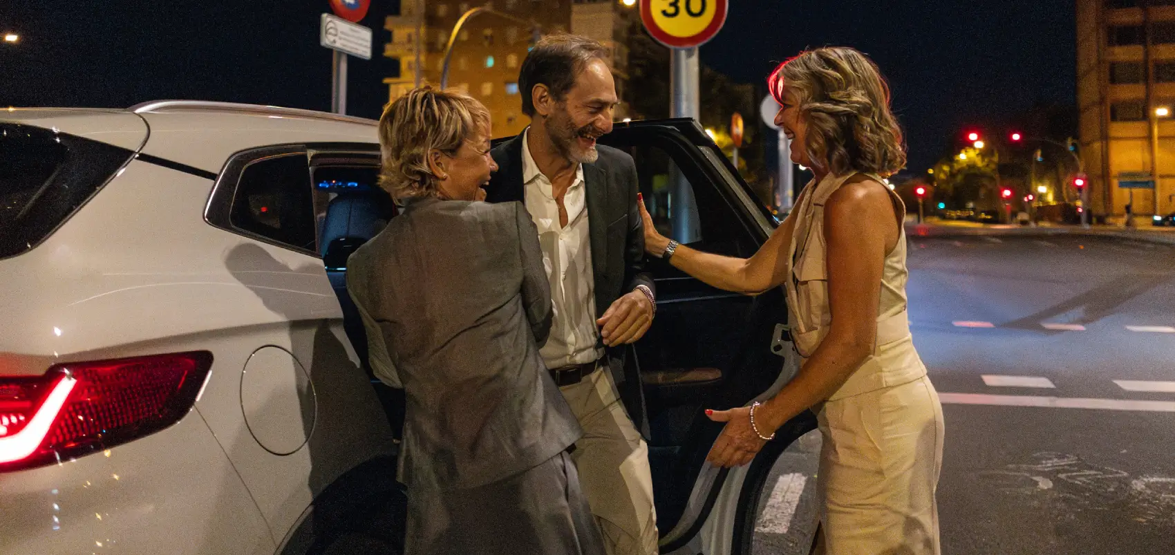 Three people chatting by a car.