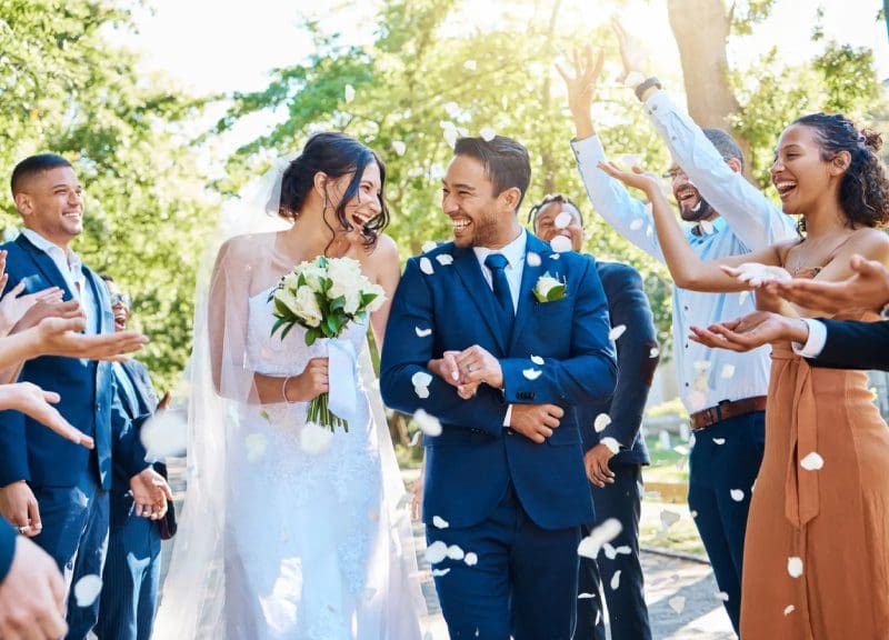 Bride and groom celebrating with guests outdoors.